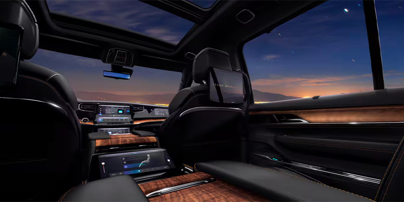 Luxurious SUV interior of the 2025 Jeep Grand Wagoneer with a panoramic sunroof and sleek controls, featuring wood accents.